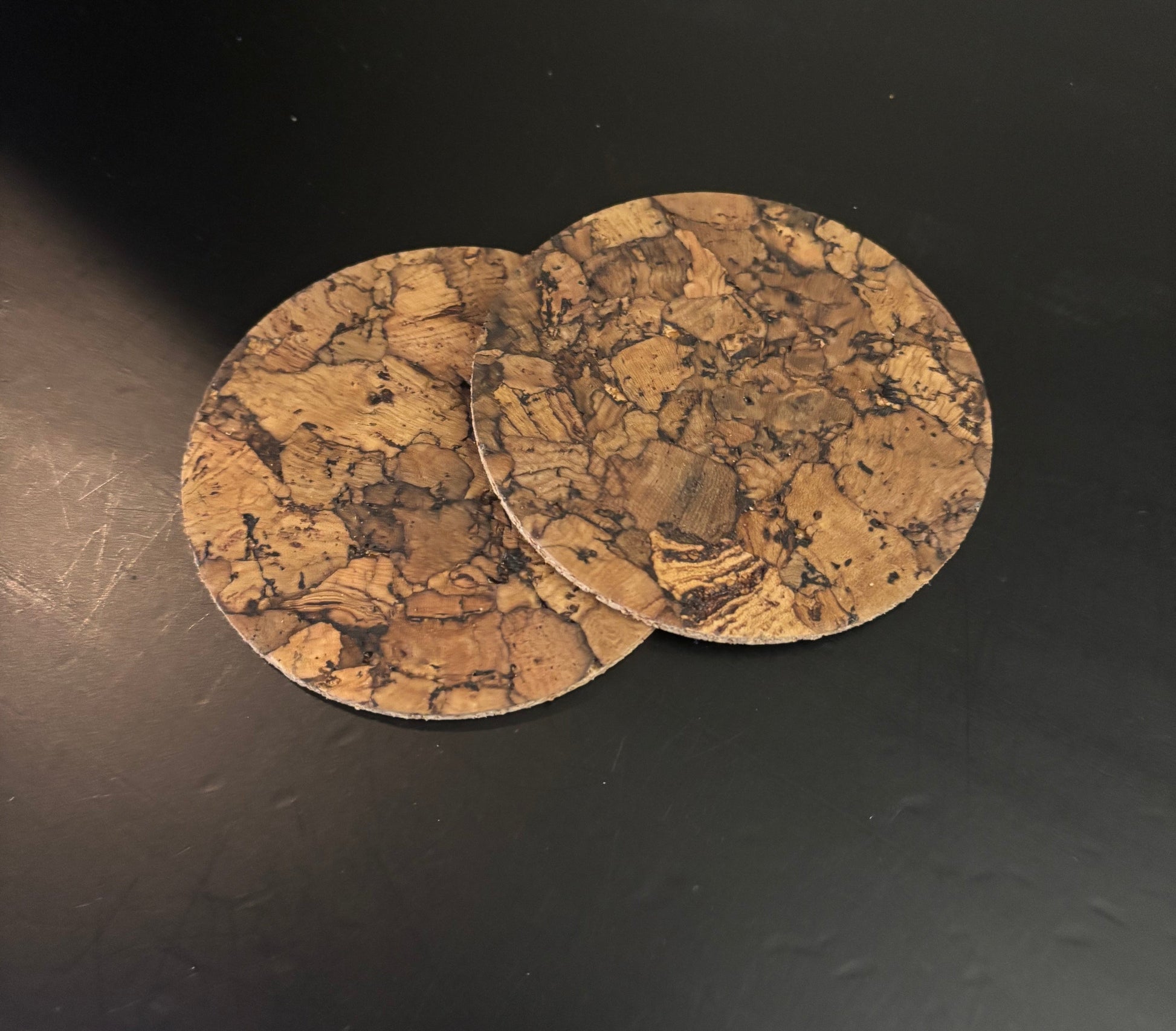 Two cork coasters on a dark surface